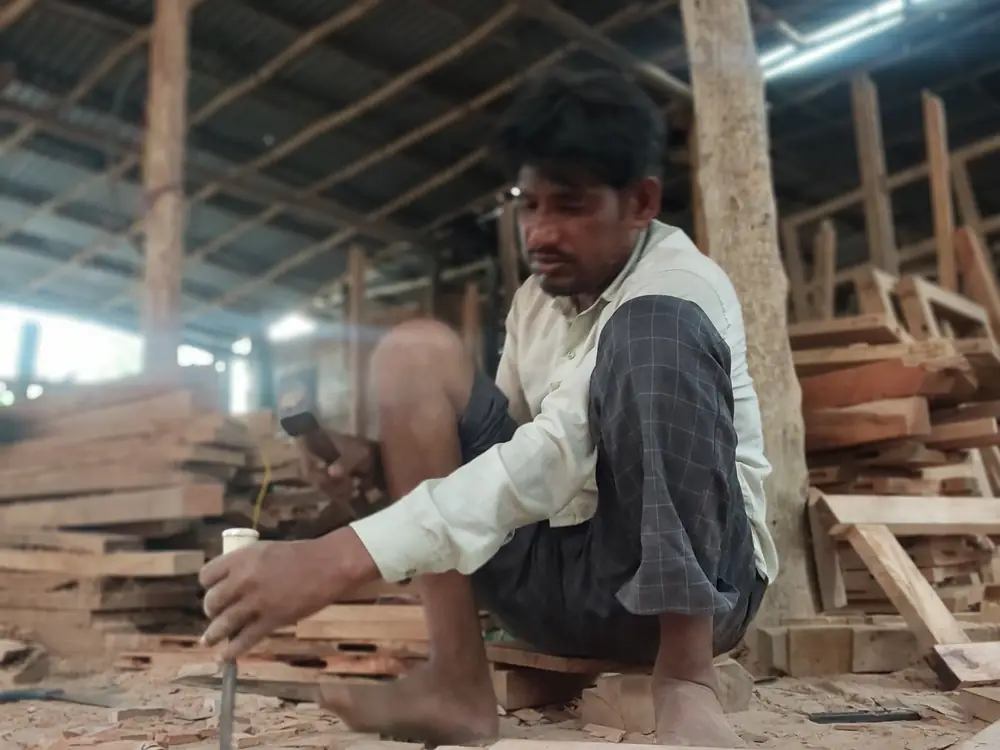 A carpenter chiselling wood in an open workshop